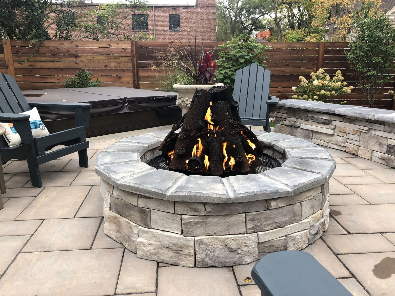 Evening fire pit with a curved stone seat wall and garden lighting