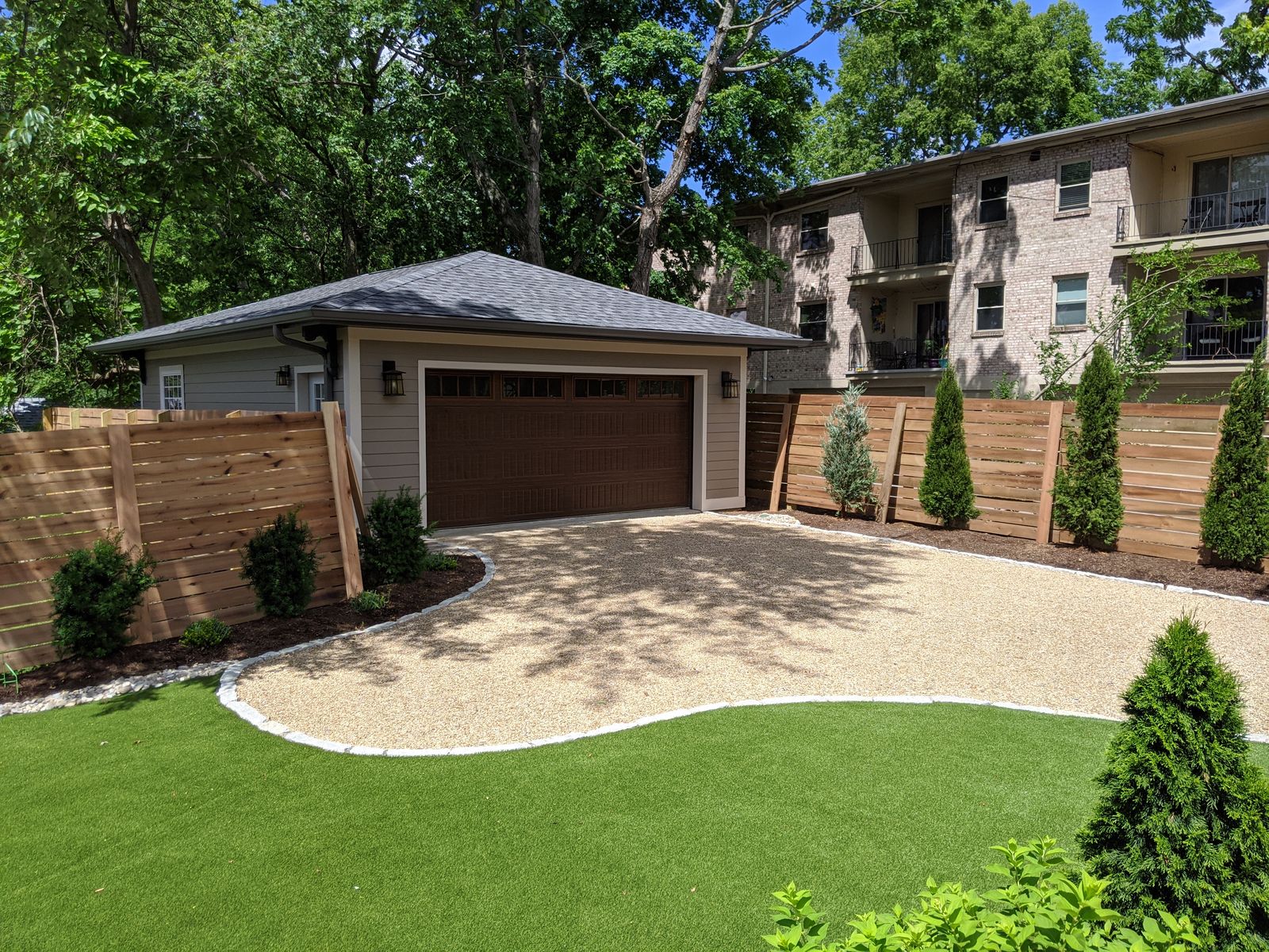 Custom detached garage with paver driveway and manicured lawn