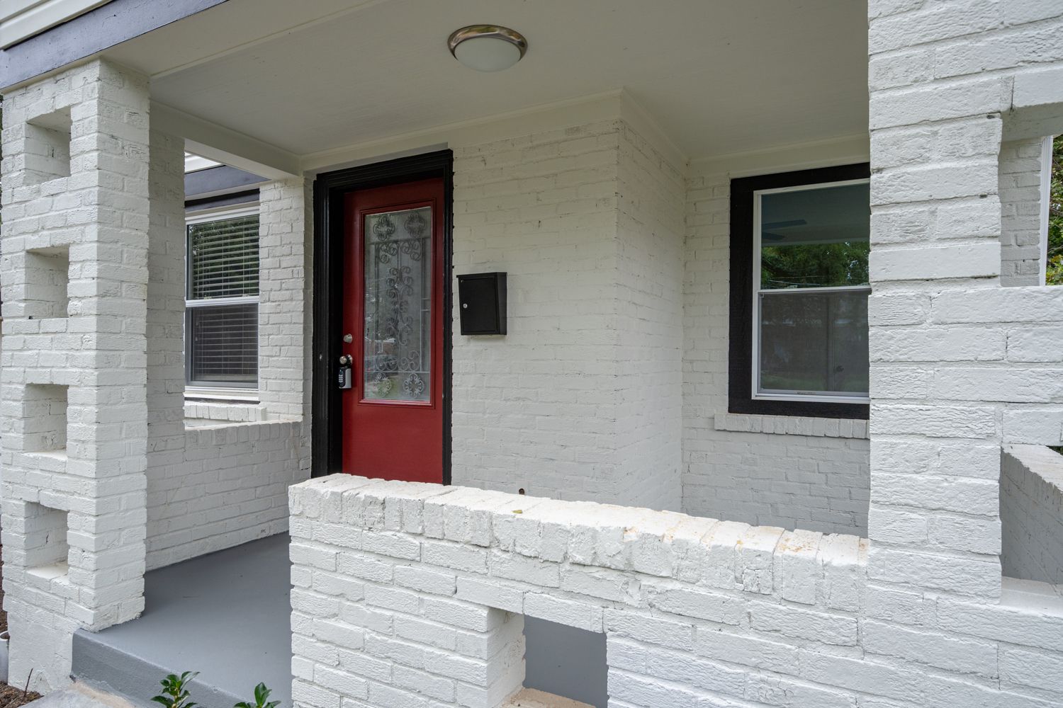 Covered front porch with white brick columns and red entry door