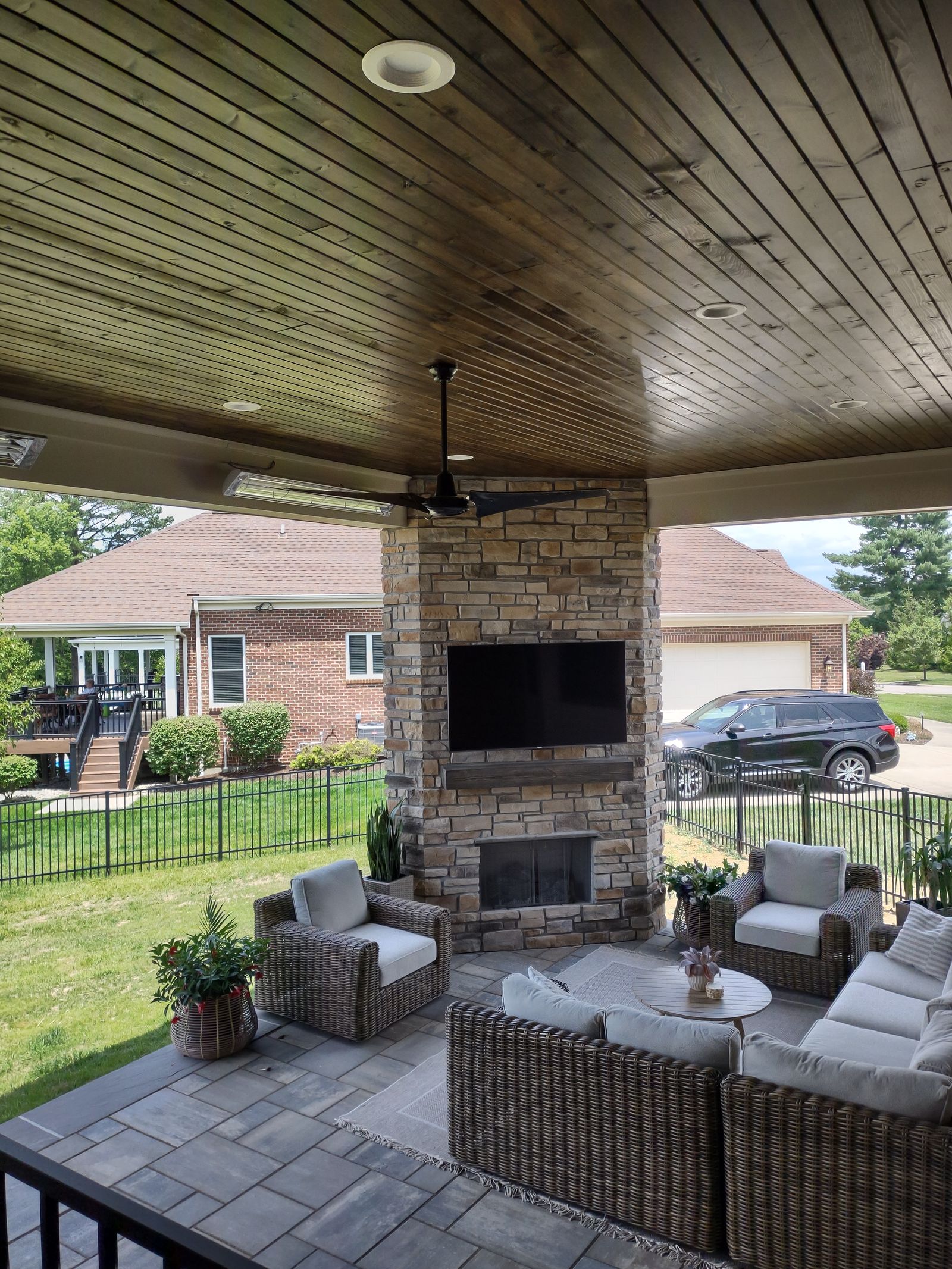 Stone fireplace and outdoor seating under a wood porch ceiling