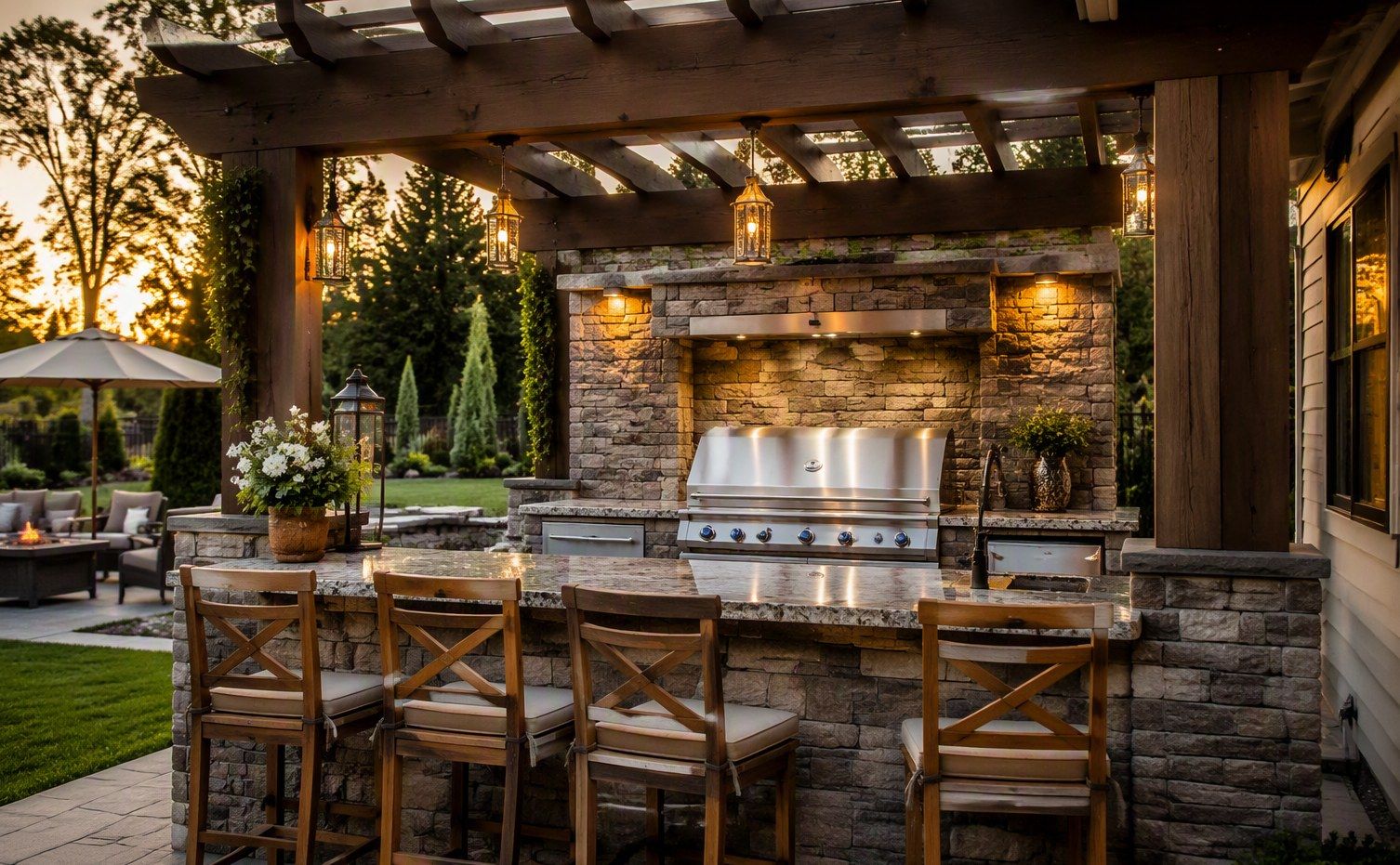 Outdoor kitchen with stone bar seating and a built-in grill under a pergola at dusk