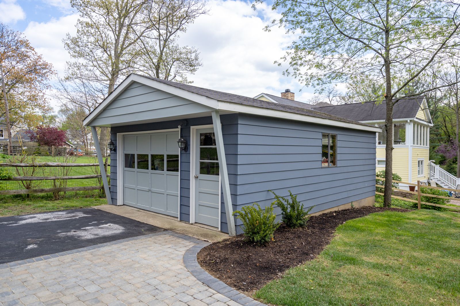 Custom detached garage with carriage-style door and paver driveway apron