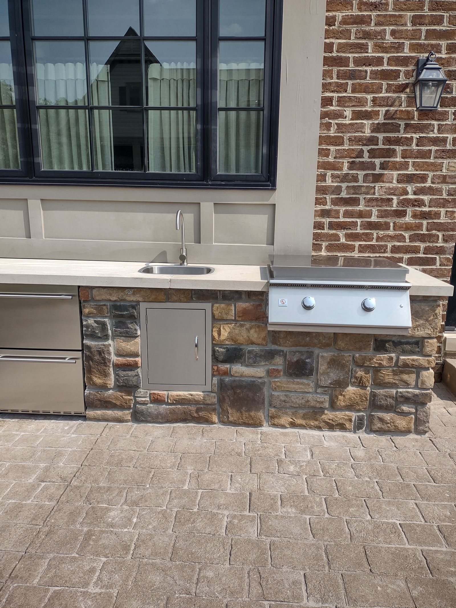 Built-in stainless grill and storage set into a stone outdoor kitchen