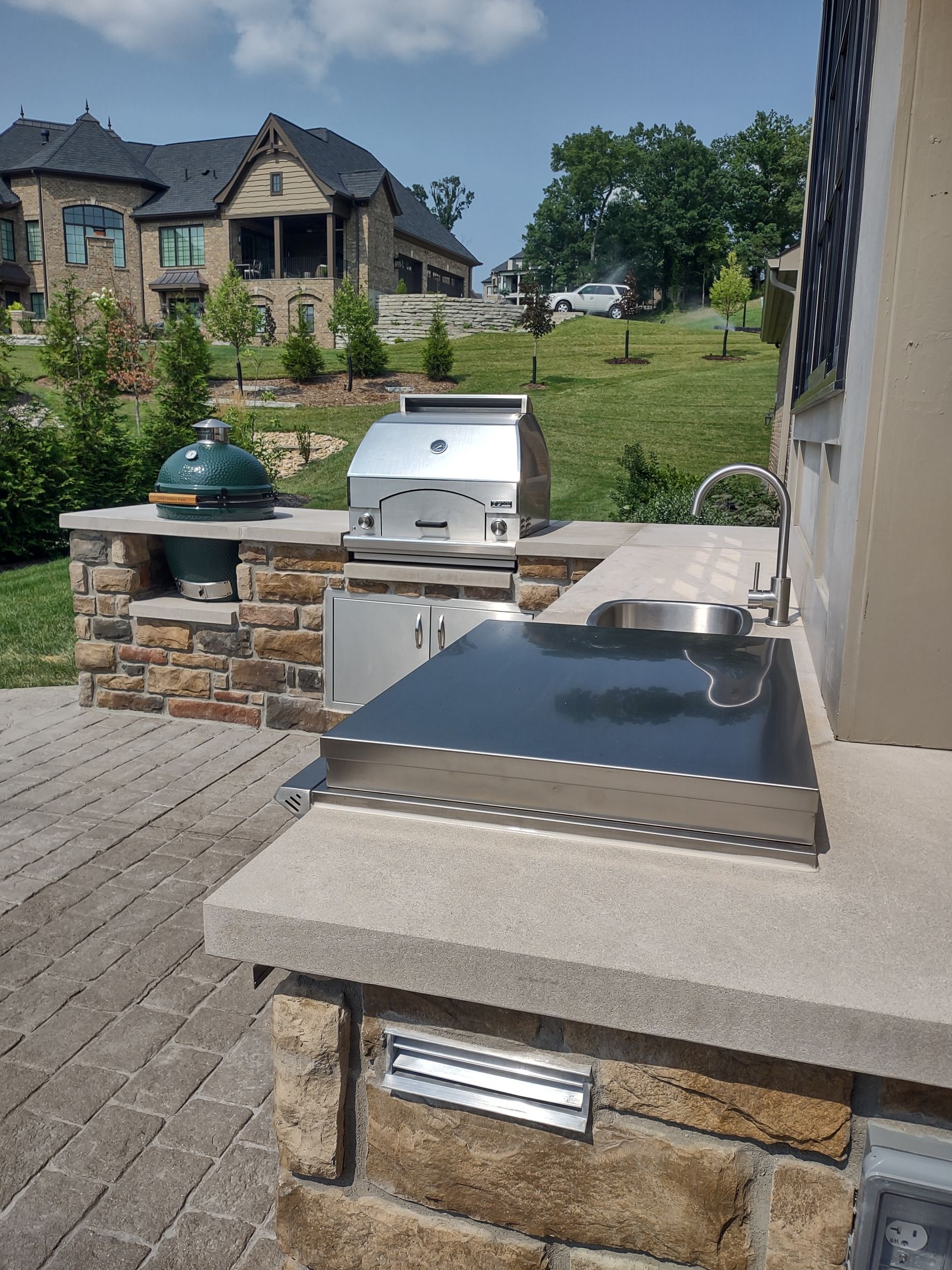 Outdoor kitchen counter run with stone cladding and paver floor
