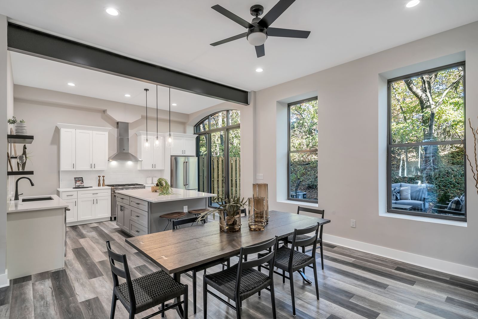 Open kitchen with island and dining table beside tall windows