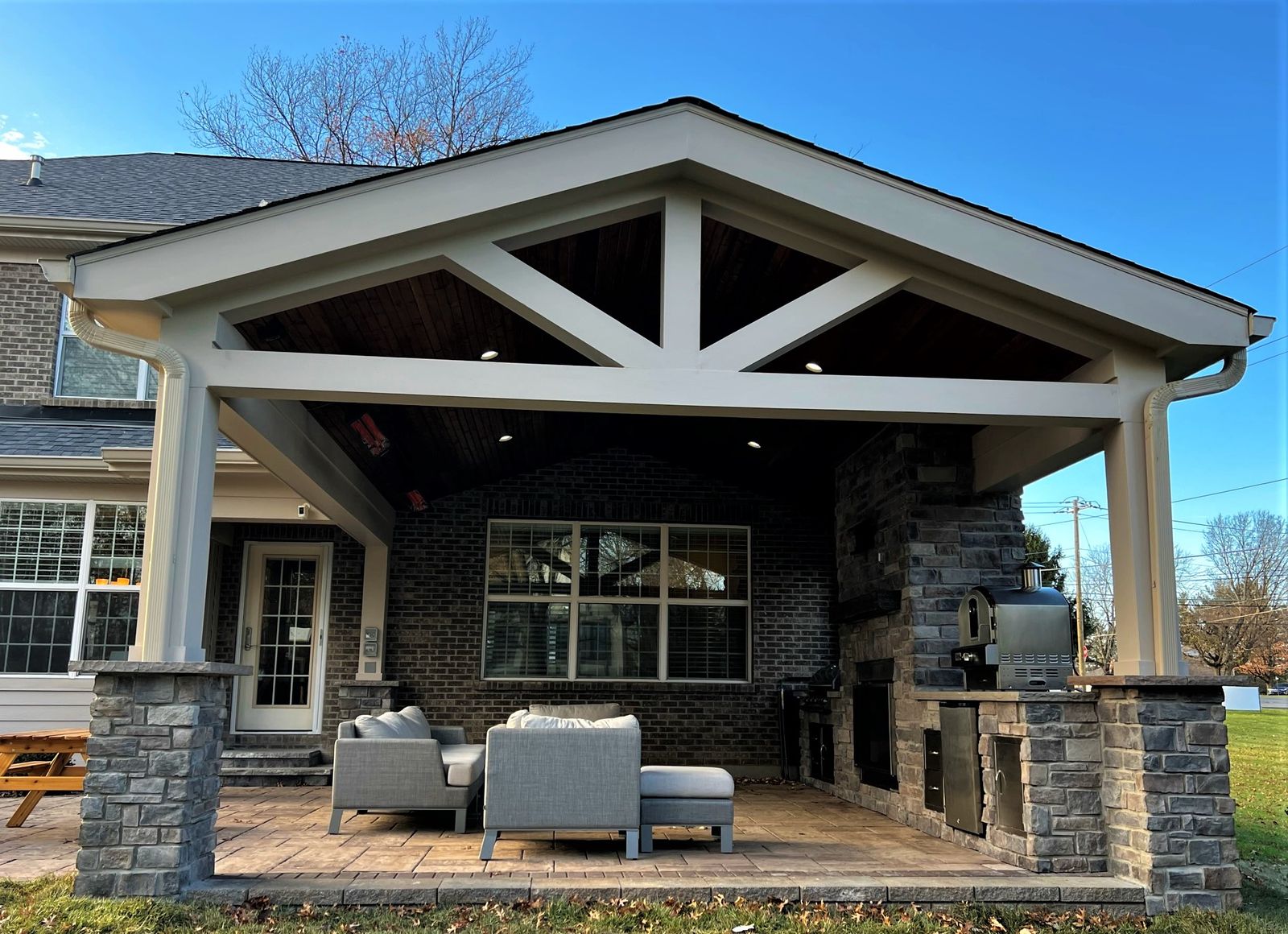 Covered gable porch with stone column bases and outdoor seating at dusk