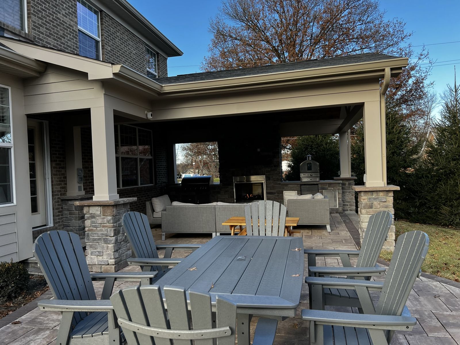 Covered porch dining area with patio table and views into the outdoor kitchen