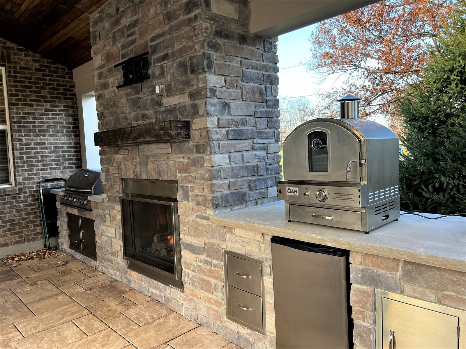 Outdoor kitchen with built-in grill, pizza oven, and stone fireplace