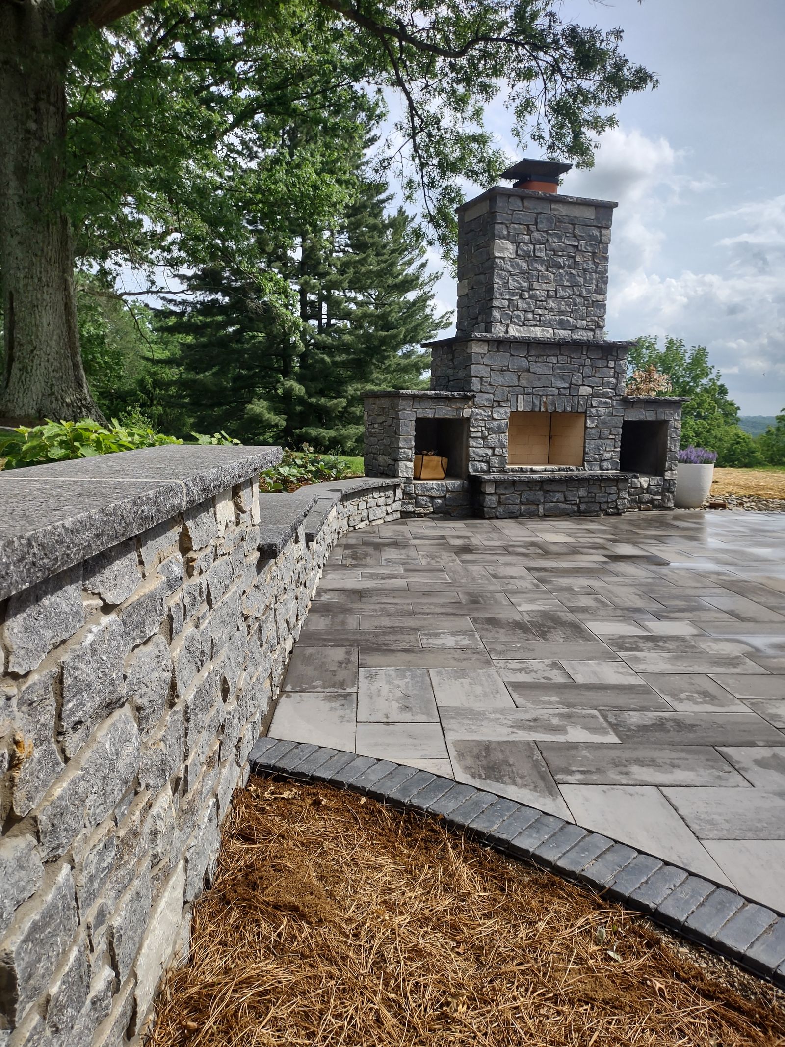 Paver patio edge with low stone seat wall and planting bed