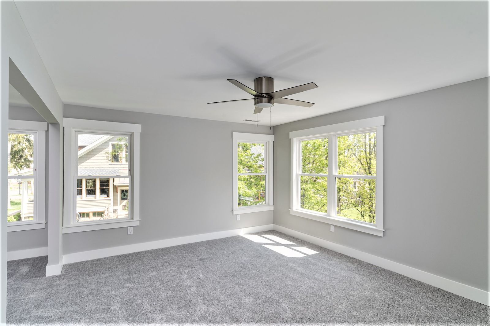 Bedroom with new carpet, ceiling fan, and two windows with backyard views