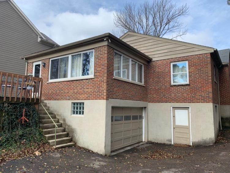 Original rear corner of the home with a garage door, side entry, and aging deck