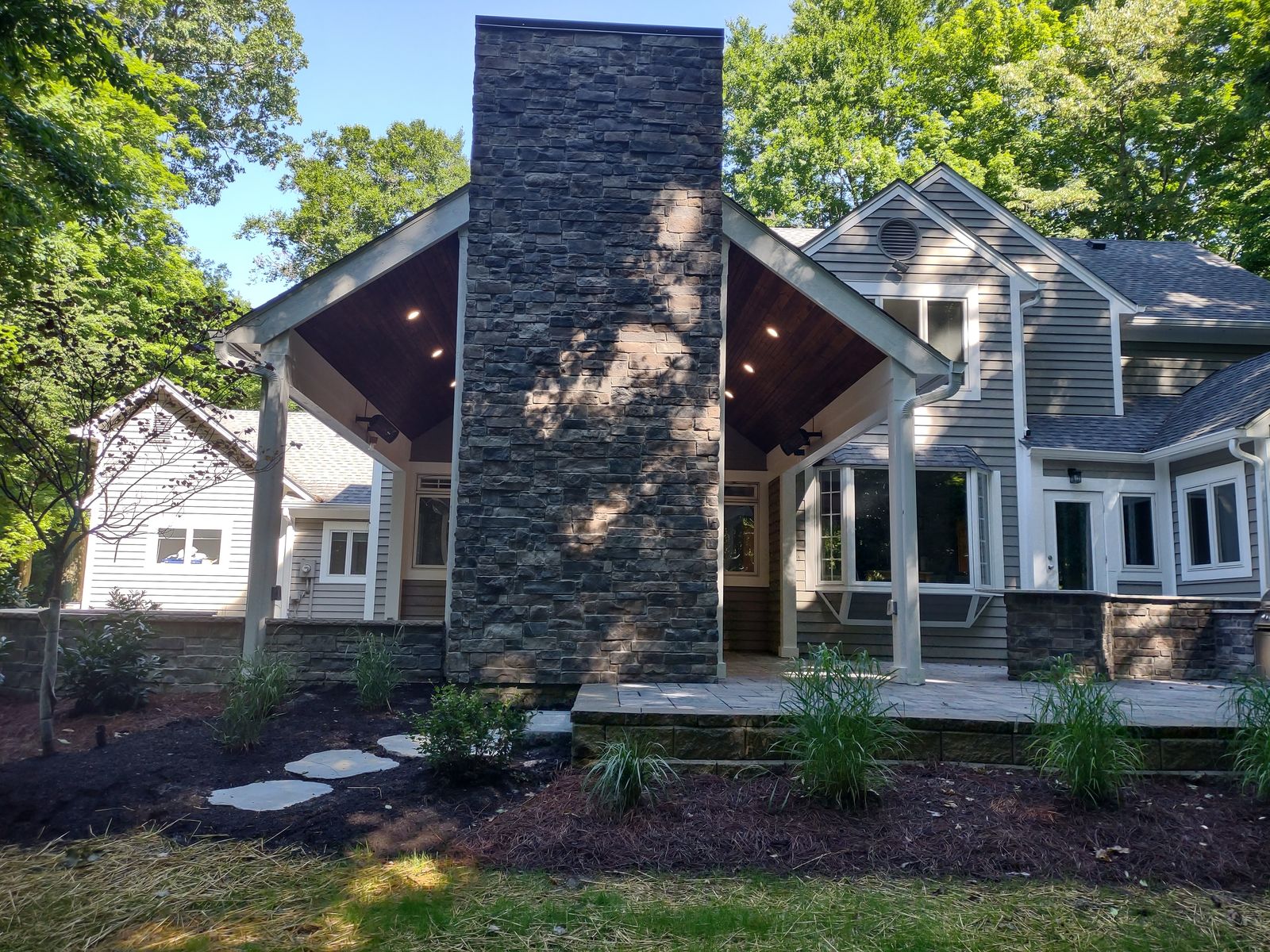 Home exterior with covered porch and tall outdoor stone chimney