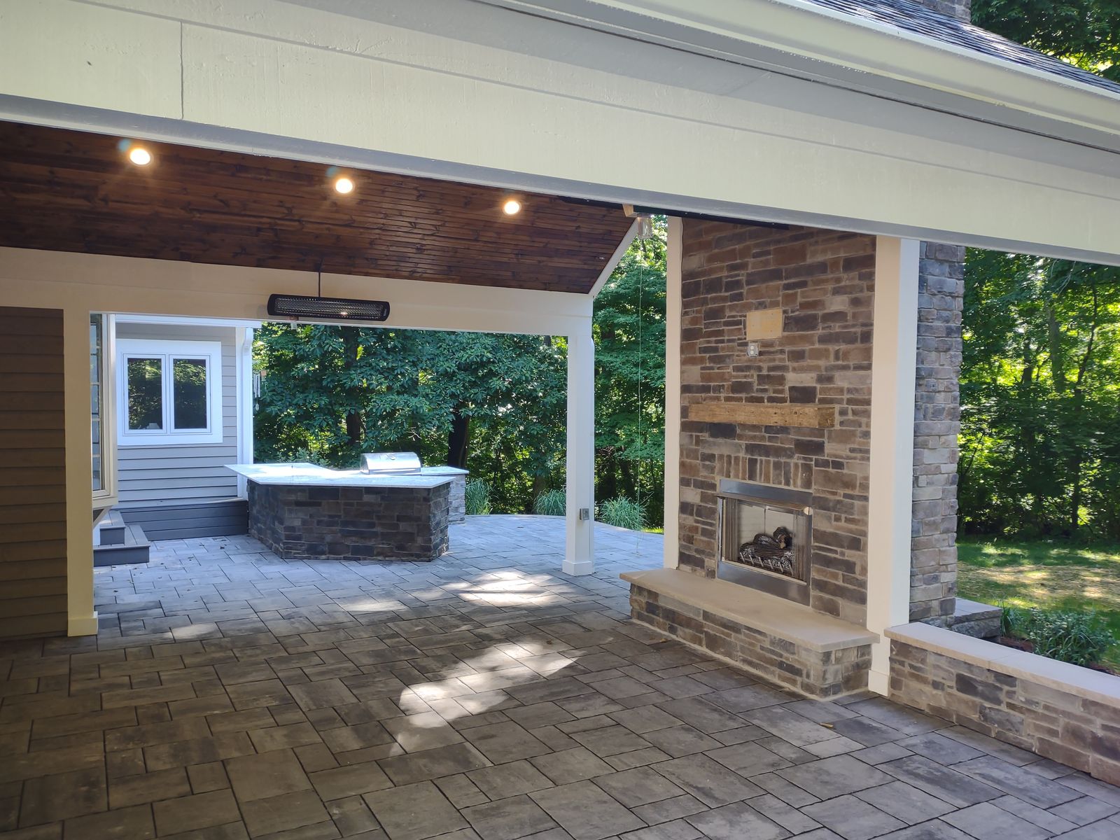 Covered porch with fireplace, wood ceiling, and recessed lighting