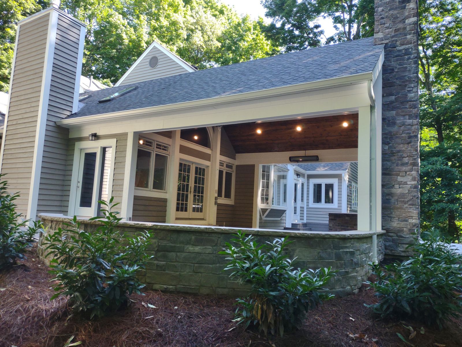 Covered porch with beadboard ceiling, recessed lights, and stone seat wall