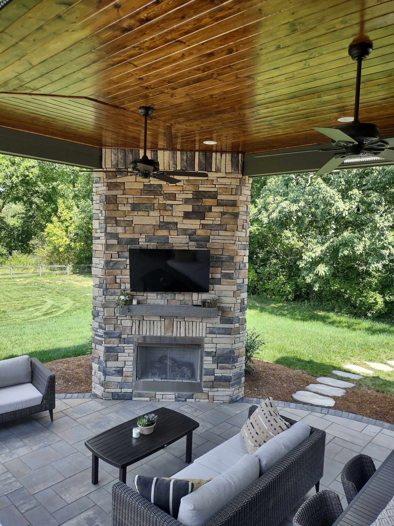 Covered lower lounge with stone fireplace and deep seating