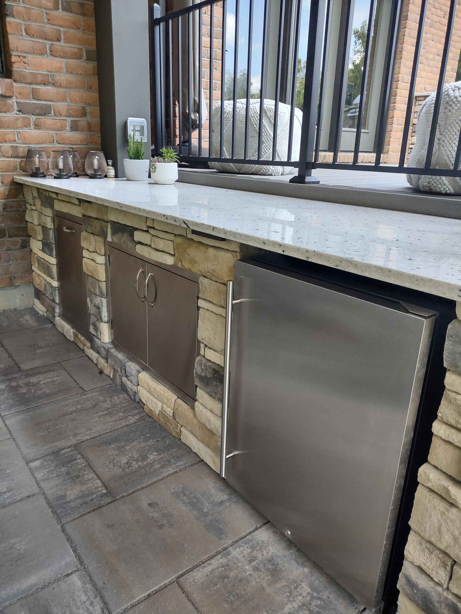 Outdoor kitchen island with stone veneer, concrete countertop, and stainless appliances