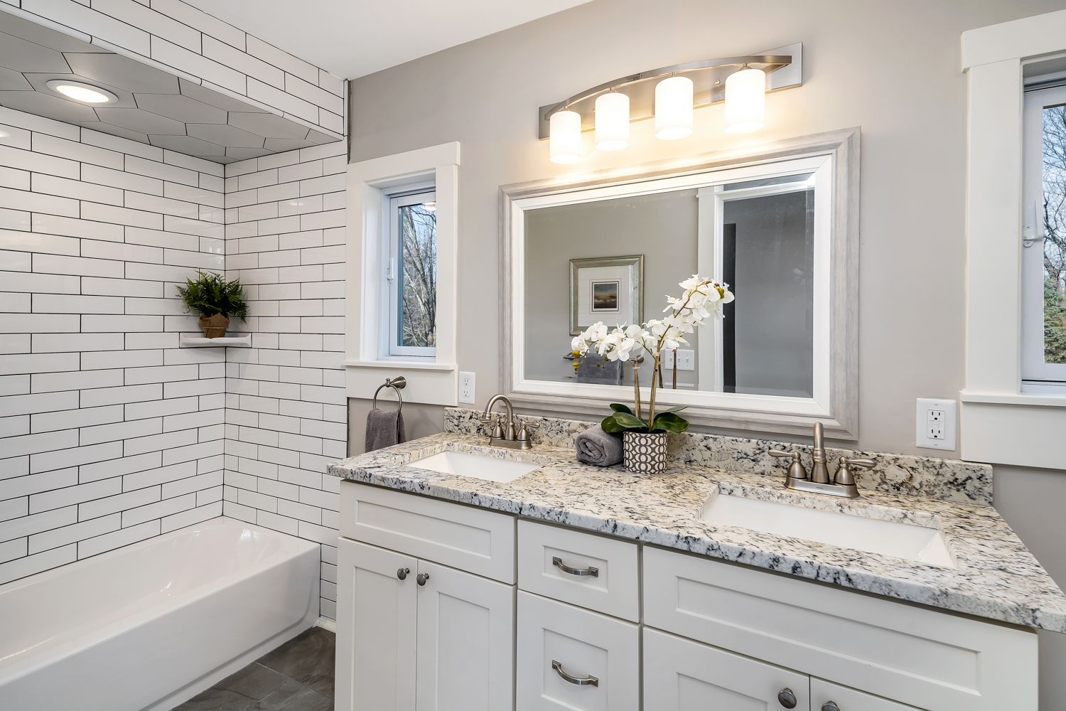 Renovated hall bath with double vanity and subway tile wainscot
