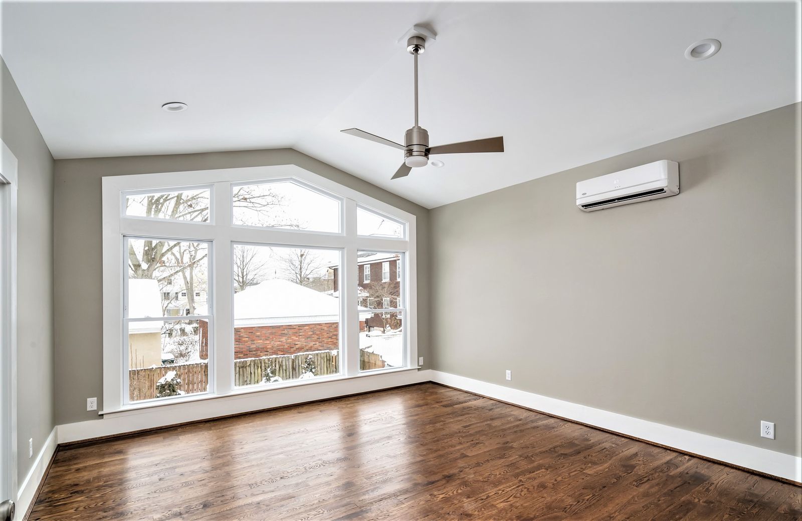 Renovated master bedroom with a wall of windows and hardwood floors