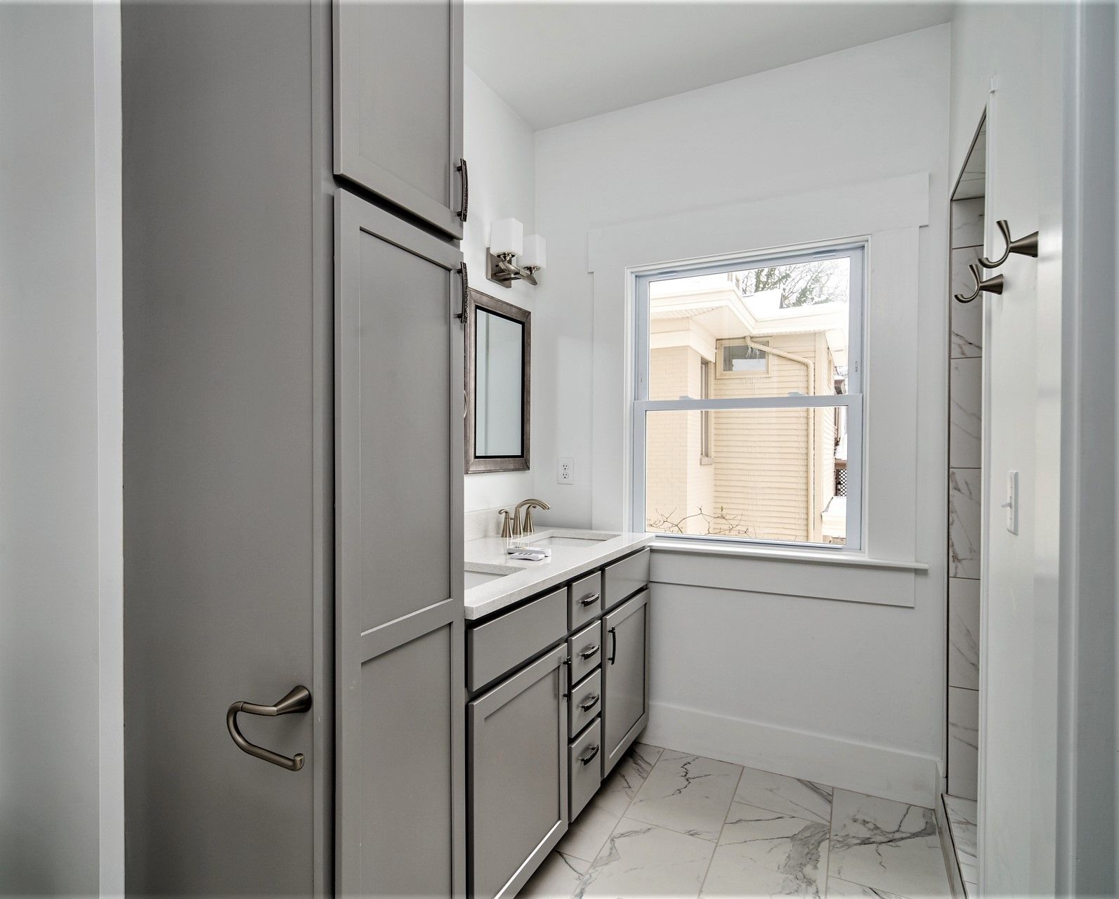 Master bath with grey cabinetry and marble-look tile
