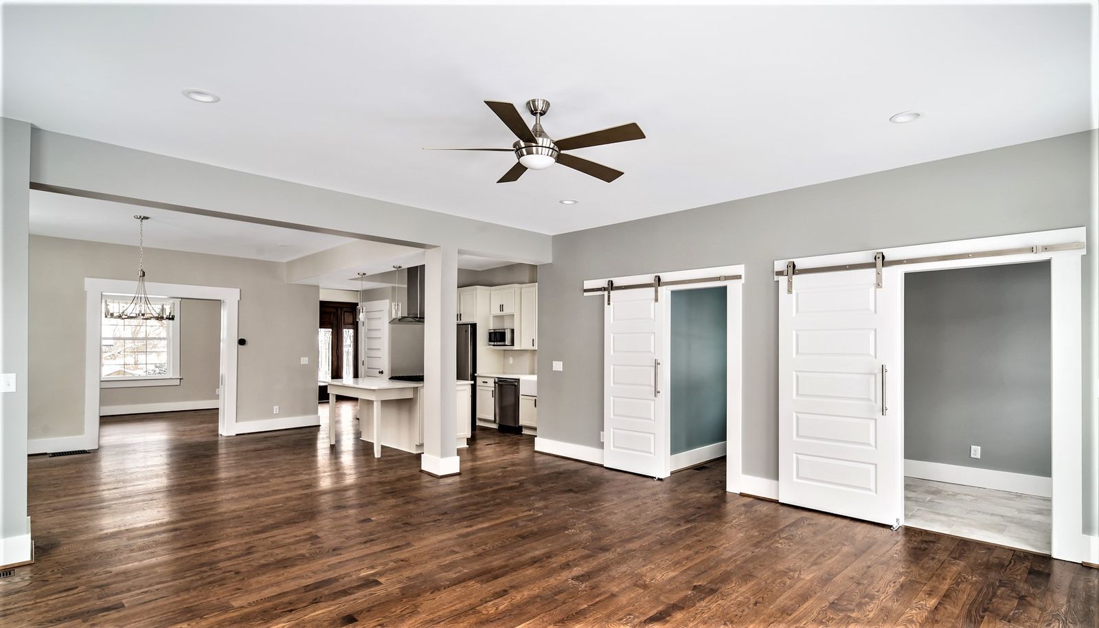 Open dining area with sliding barn doors and view into the kitchen