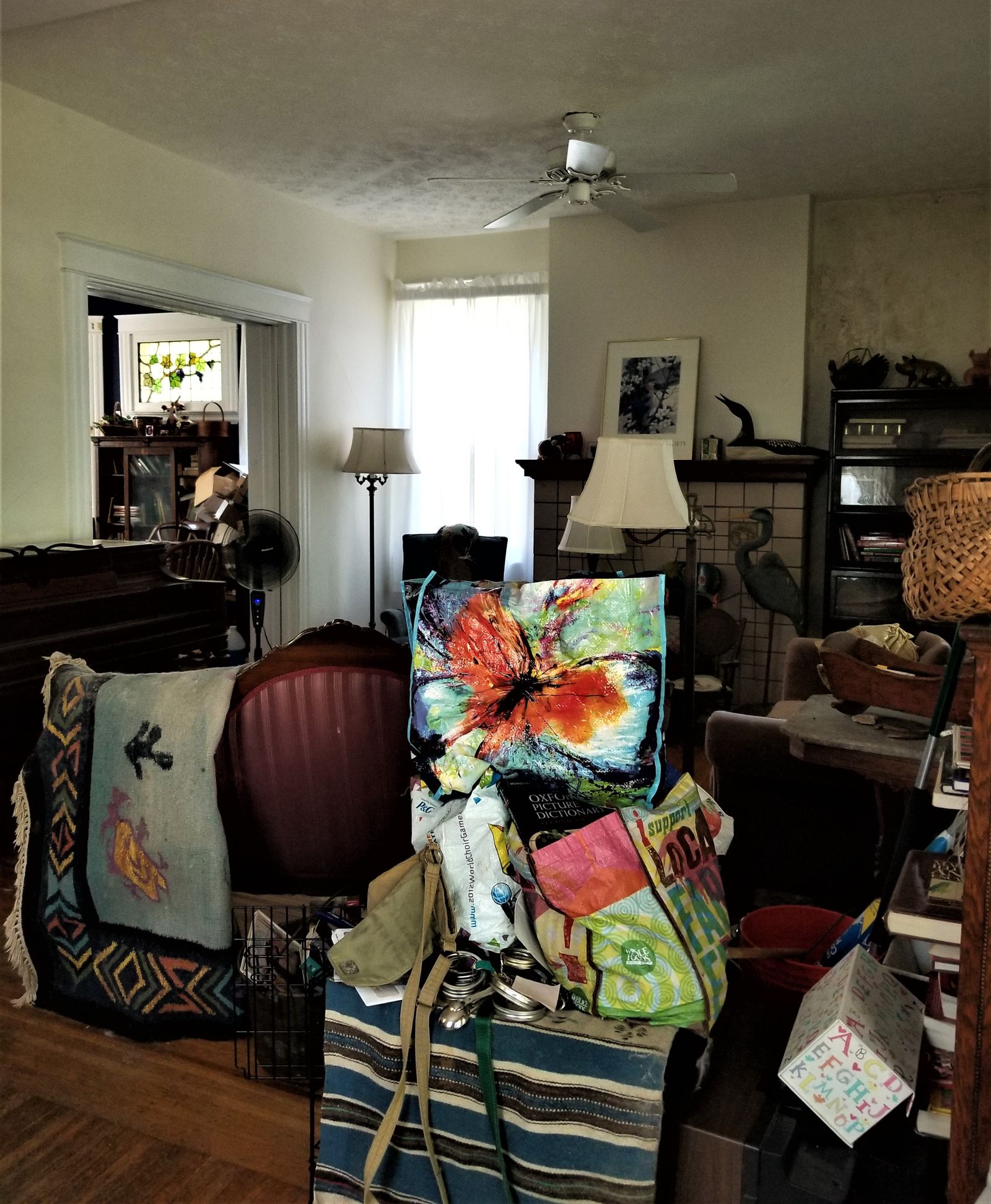 Cluttered living room with original tile fireplace before renovation